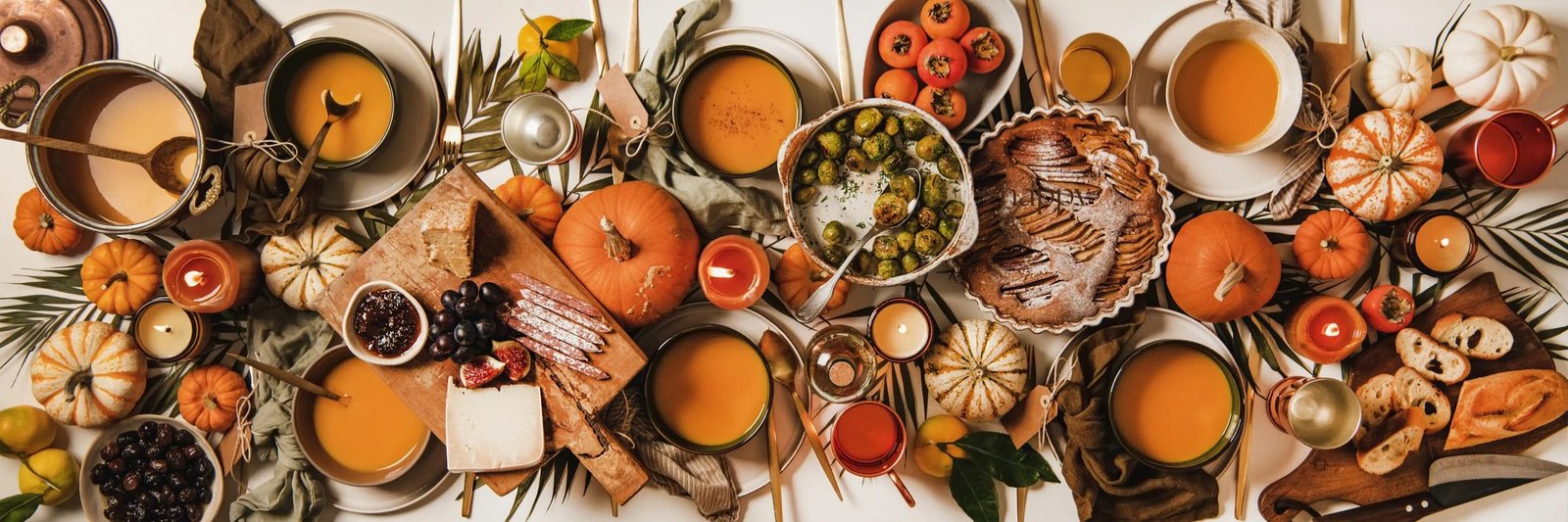 Overhead view of a Thanksgiving table with soups, pumpkins, roasted vegetables and pie